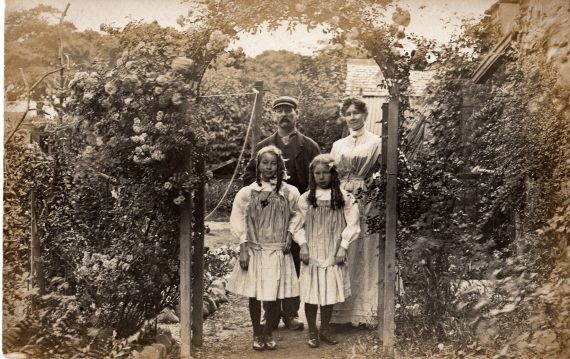 Black-and-white postcard of garden with family, late nineteenth century